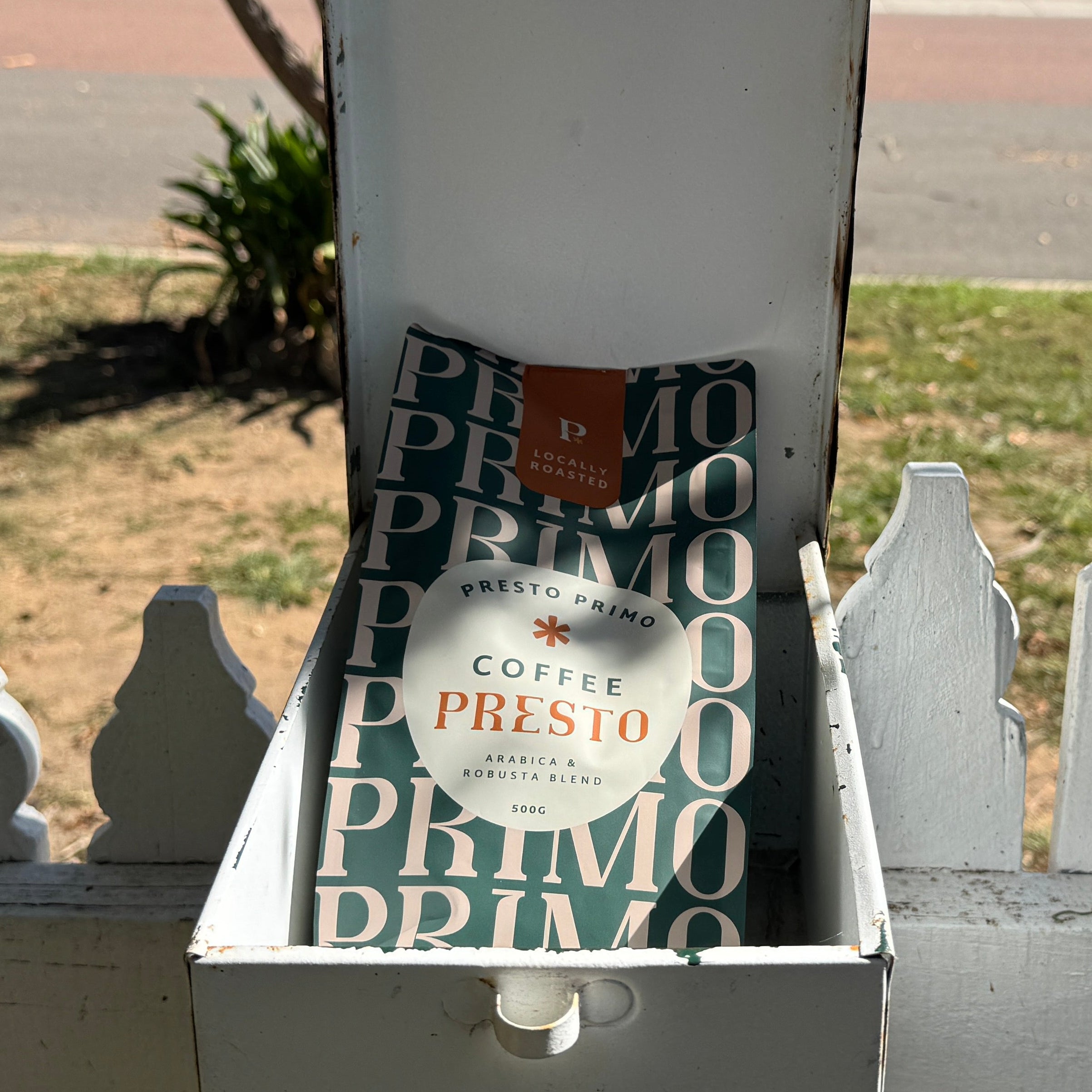 Mailbox with Primo coffee packages on a white picket fence