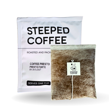 A package of Steeped Coffee Roasted and Packaged coffee next to a single brewed coffee bag with a white tag, on a clean white background.